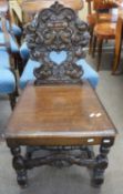 A 19th Century heavily carved oak hall chair raised on a turned frame, 90cm high