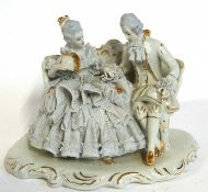 A continental porcelain model of a lady and gentleman seated on a bench on white scroll and gilt