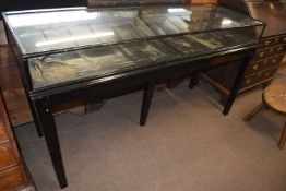 An early 20th Century large counter bijouterie cabinet with mirrored back doors set on a black