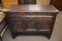 An antique oak side cabinet with a single drawer over two panelled doors and decorated with carved