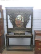 Late Victorian gothic carved hall stand with central oval mirror and glove drawer, extensively