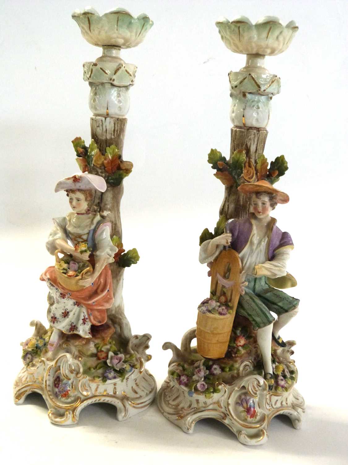 A pair of continental porcelain candlesticks, possibly Sitzendorf, modelled as a boy and girl