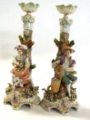 A pair of continental porcelain candlesticks, possibly Sitzendorf, modelled as a boy and girl