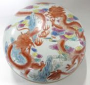 A large Chinese circular bowl and cover decorated with a dragons in iron red amongst foliage, the