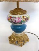 A table lamp mounted on a gilt decorated base with painted or printed floral design to the