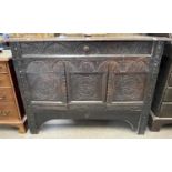 An antique oak side cabinet with a single drawer over two panelled doors and decorated with carved