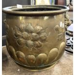 Circular brass jardiniere decorated with heraldic detail and lions head handles (lacking