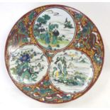 Oriental pottery dish with three panels of design in famille verte amongst intricate floral borders,