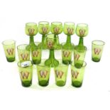 Group of green glass wares with enamelled WE monogram, comprising six wine glasses and ten smaller