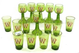 Group of green glass wares with enamelled WE monogram, comprising six wine glasses and ten smaller