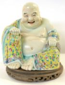 A late 19th Century Chinese porcelain figure of a smiling Buddha, the yellow ground with