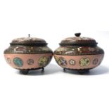 A pair of Cloisonne bowls and covers raised on three stub feet with typical floral decoration, the