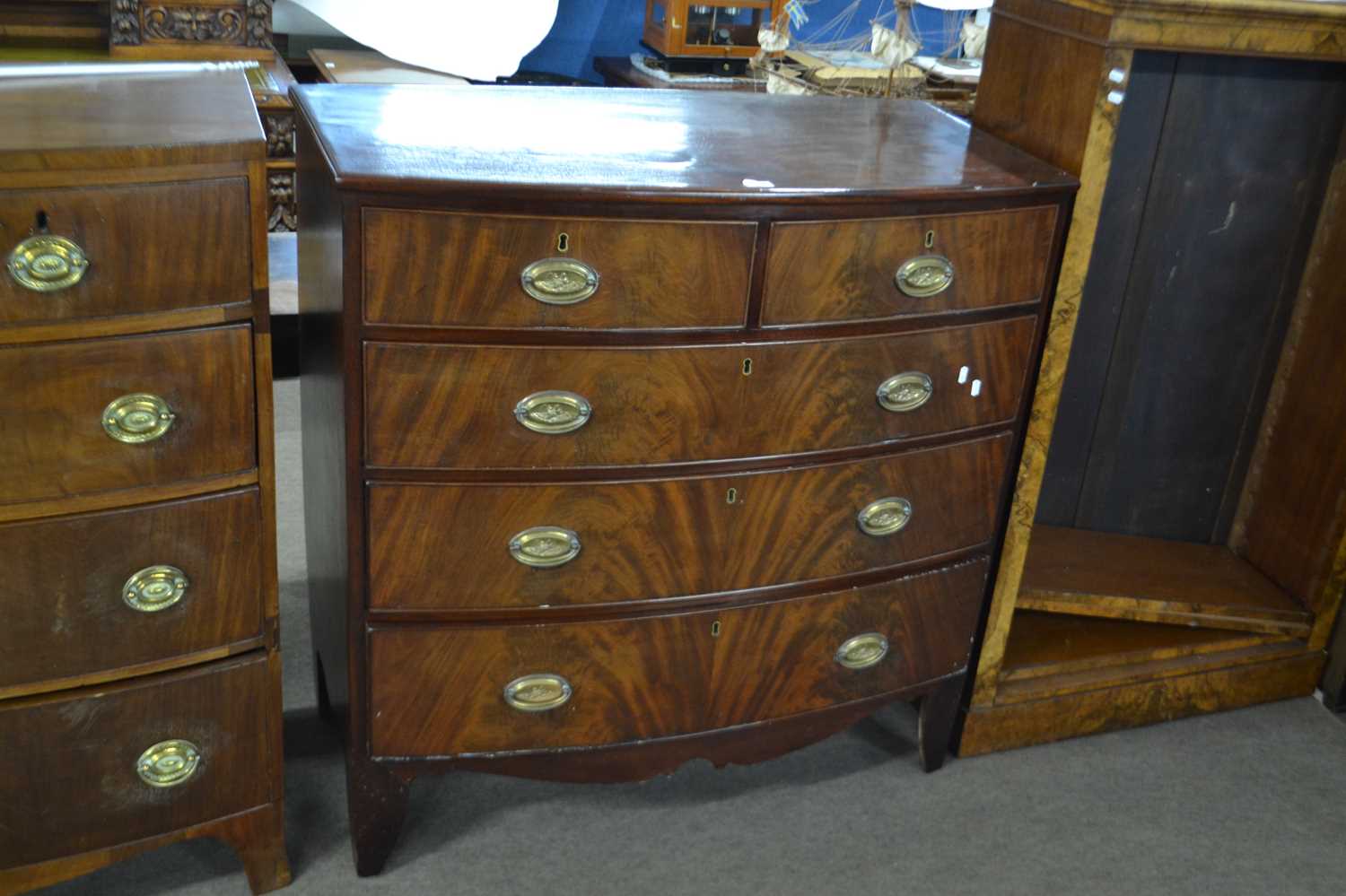 A late Georgian mahogany bow front chest of two short over three long drawers fitted with oval brass