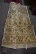 A large contemporary Middle Eastern wool floor rug decorated with stylised foliage on a beige