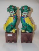 A pair of Chinese pottery temple dogs in Sancai colours on rectangular bases, 36cm high