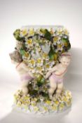 A large 19th Century porcelain vase or lamp base, the vase supported by three putti amongst floral