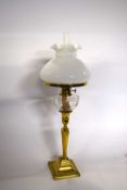 A brass oil lamp with white glazed shade and glass reservoir together with a brass Art Nouveau