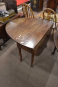 A Georgian oval oak drop leaf dining table raised on tapering legs with pad feet, 104cm wide when
