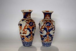 A pair of Japanese porcelain vases in Imari type designs with dragons modelled in relief, 28cm high