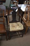 An 18th Century oak elbow chair with solid seat and stretcher base, several repairs and