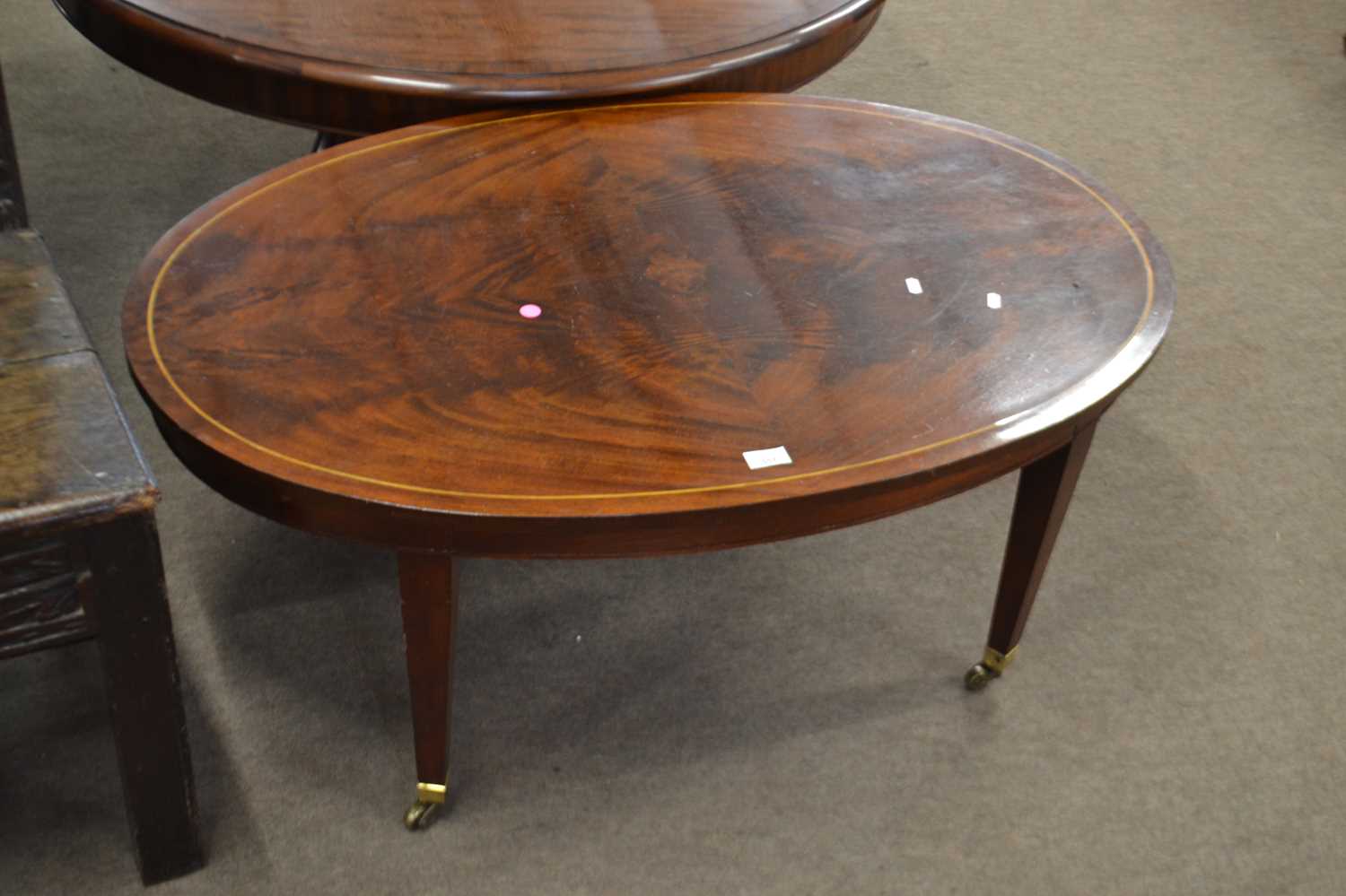 An Edwardian oval mahogany and inlaid coffee table raised on tapering legs with brass end caps and