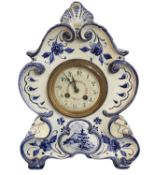 An early 20th Century Delft shaped mantel clock, the dial with painted floral decoration to the