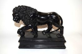 Black painted ceramic model of a Medici lion on a rectangular base, 30cm long