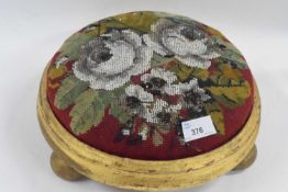 A Victorian embroidered footstool in circular gilt wooden frame