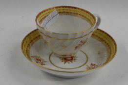 An 18th Century porcelain cup and saucer of wrythen shape with gilt and red enamel decoration