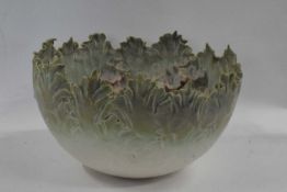 A pottery bowl with shaped rim, the interior with applied floral decoration, 24cm diameter