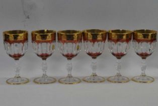 A group of Italian crystal wine glasses with purple overlay and gilt design above a knopped stem,