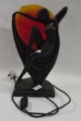 A Art Deco style model of a girl with a lamp in the background, on semi-circular green painted base