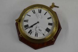 A ships clock in brass case mounted on shaped wooden base