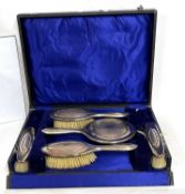 George V silver mounted cased dressing table set comprising a hand mirror, two hairbrushes and two