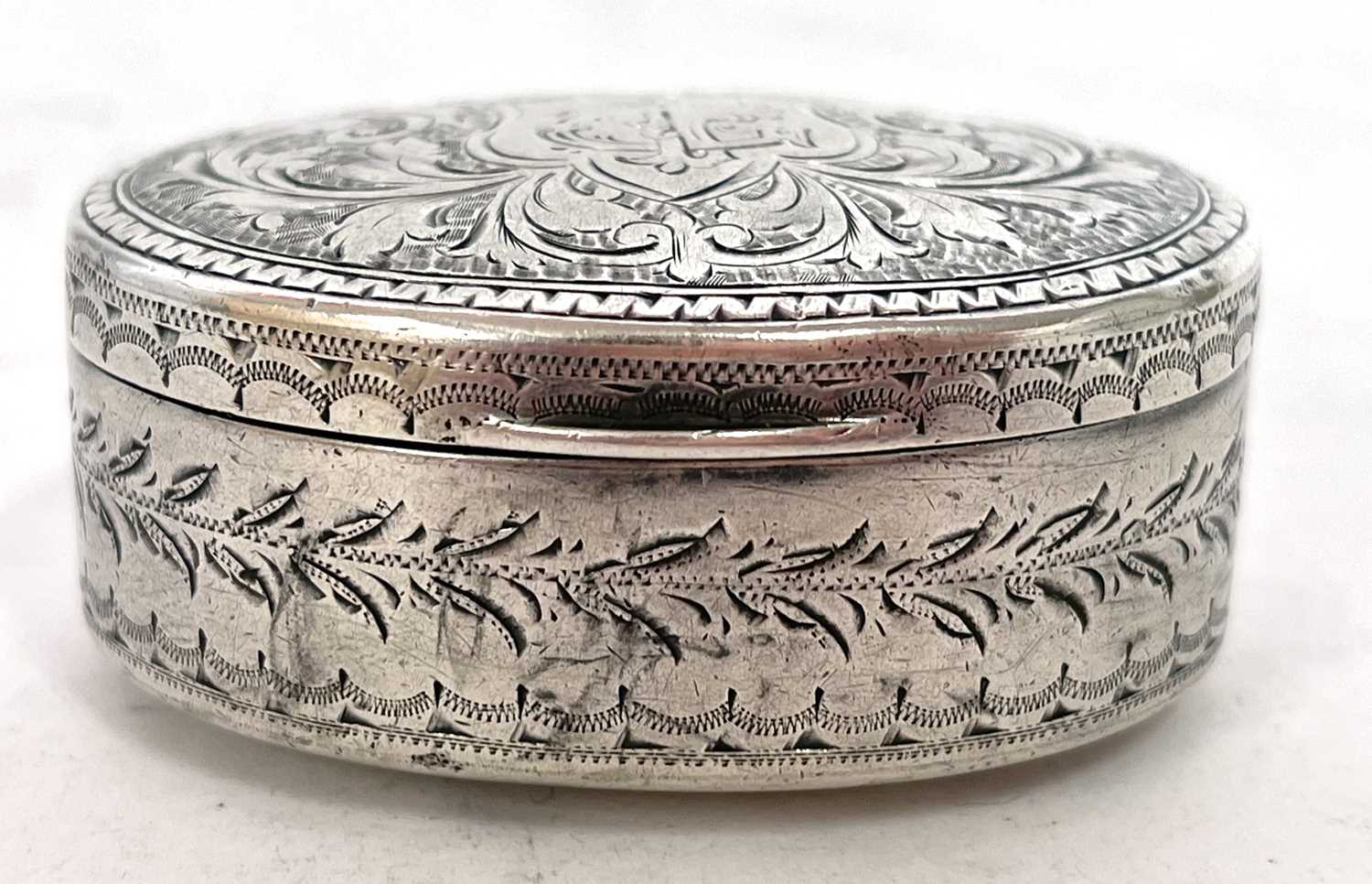 Edwardian silver snuff box of oval form, the hinged lid chased and engraved all over with scrolls