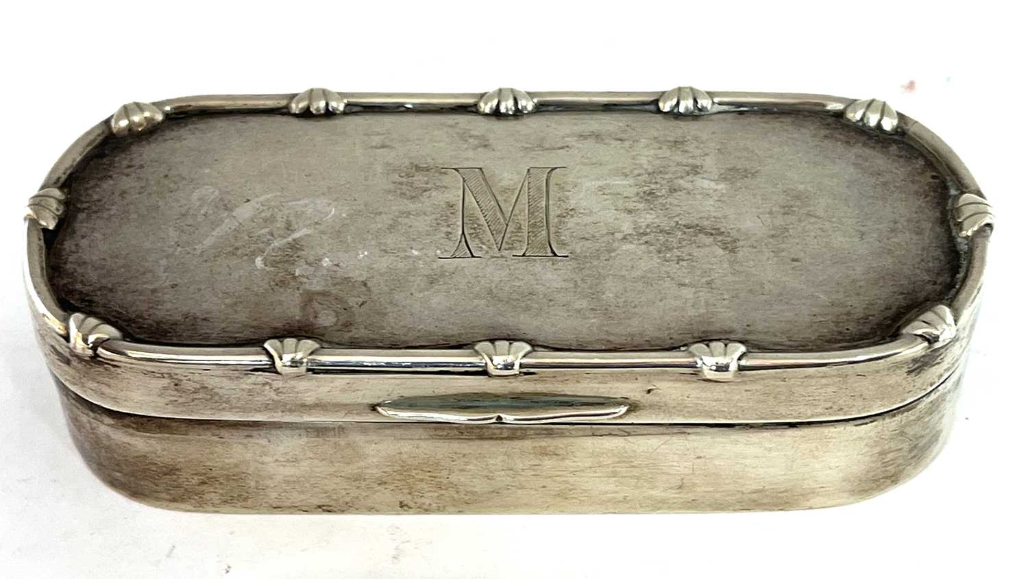 Edwardian silver trinket box of shaped rectangular form, applied with a bow and reeded border to