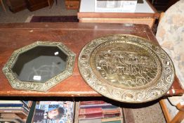 An octagonal bevelled wall mirror in brass finish frame together with a pressed brass charger (2)