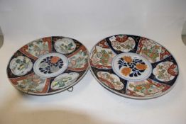 Two Japanese porcelain chargers with polychrome designs of island scenes and flowers, largest 40cm