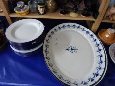 Two large oval enamel serving dishes together with a selection of white enamel plates