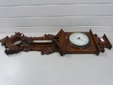 A large and elaborate late 19th Century barometer and thermometer set in a heavily carved case (a/