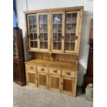 20th Century pine dresser with glazed top section over a base with four drawers and four doors,