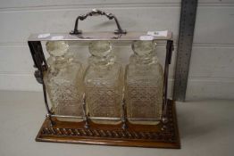 A silver plated and oak tantalus with three decanters