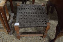 A small square footstool with mesh top