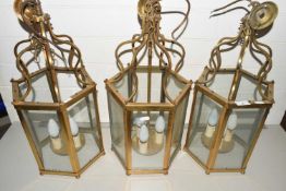 A set of three 20th Century hexagonal brass and glass lantern style light fittings