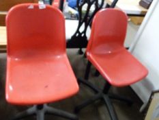 Pair of red plastic swivel office chairs