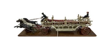 A complete reproduction cast iron fire cart with detachable ladder, orignal riders and three