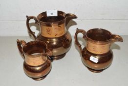 Graduated set of three copper lustre jugs