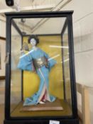 A cased model of a Geisha in blue Komono with gold Obi
