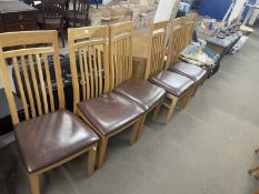 A set of six oak dining chairs with brown leatherette seats