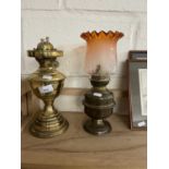 Two brass oil lamps, one with frosted orange shade